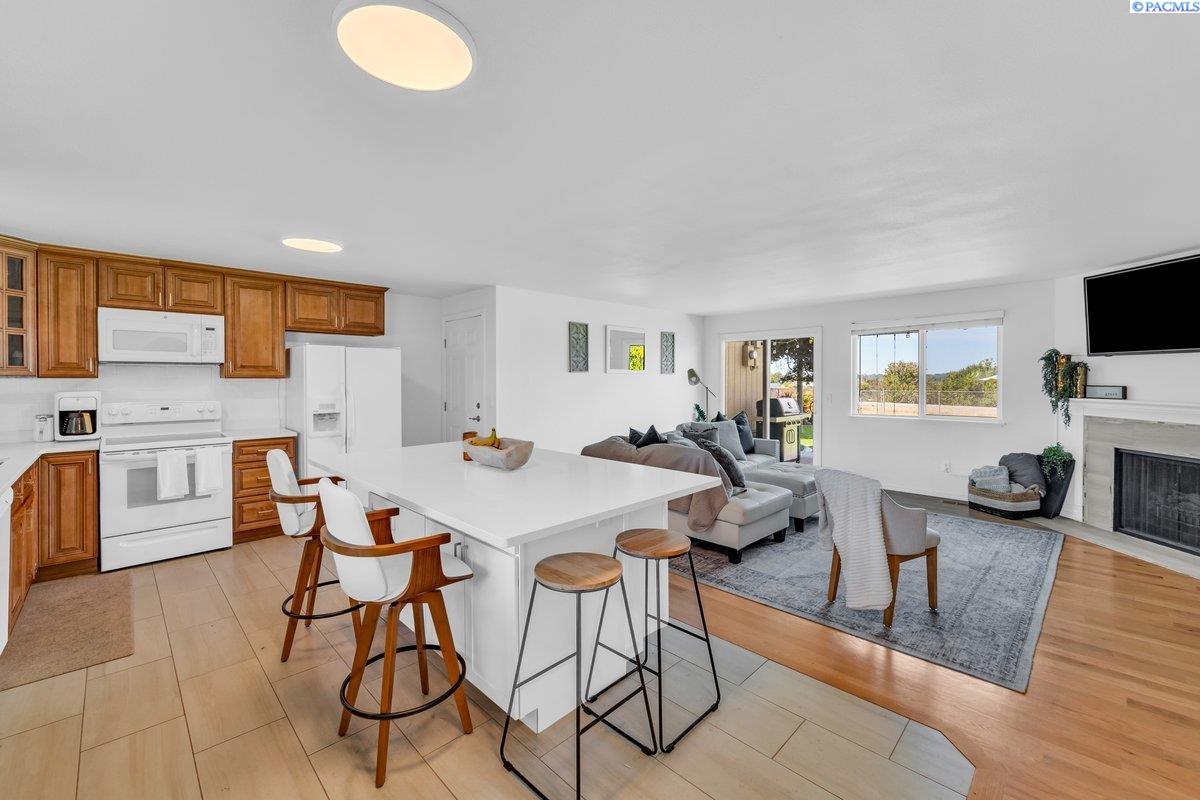 Open-plan kitchen and living room with a large island, wood cabinetry, and gray seating.