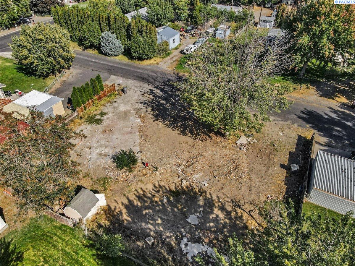 Aerial view of a cleared residential lot bordered by trees, fences, and neighboring homes.