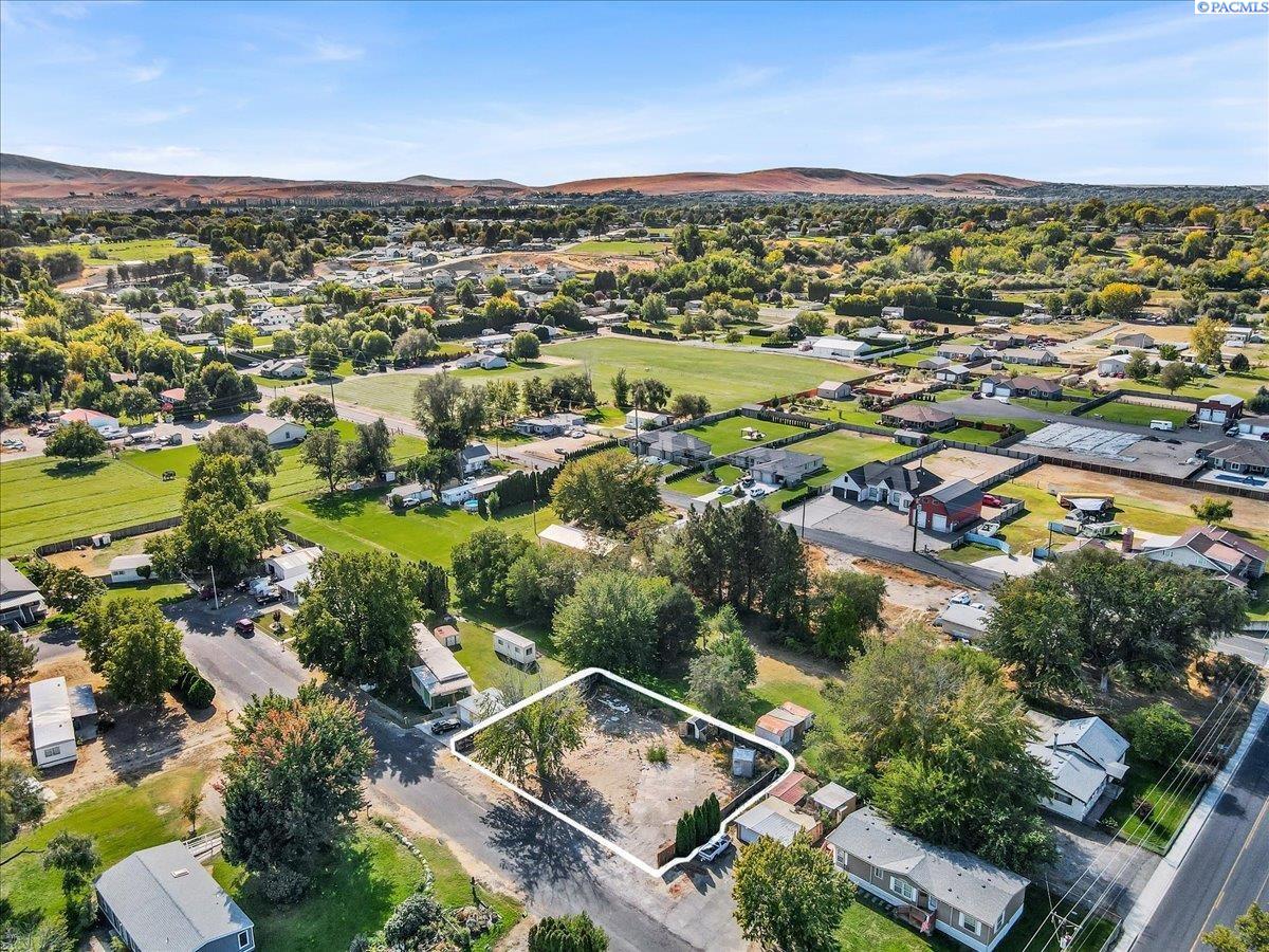 Aerial view of a cleared lot outlined in white, surrounded by homes and tree-lined streets.