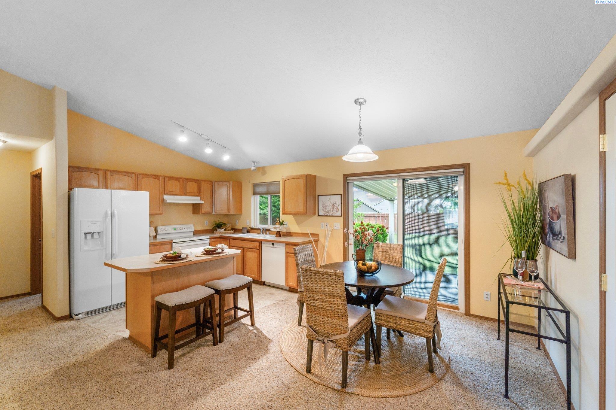 Kitchen and dining area with wood cabinetry, breakfast island, and sliding patio doors.