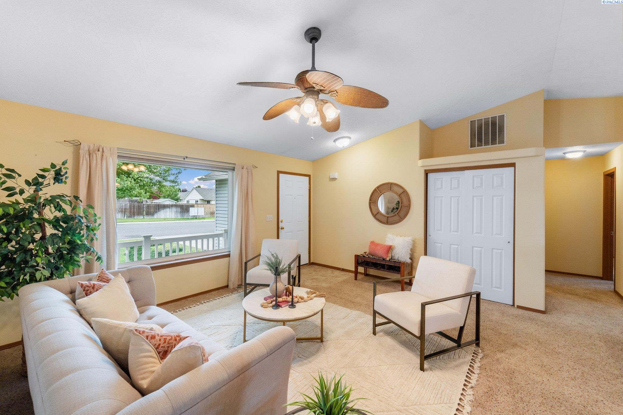 Furnished living room with yellow walls, a white sofa, and a large street-facing window.