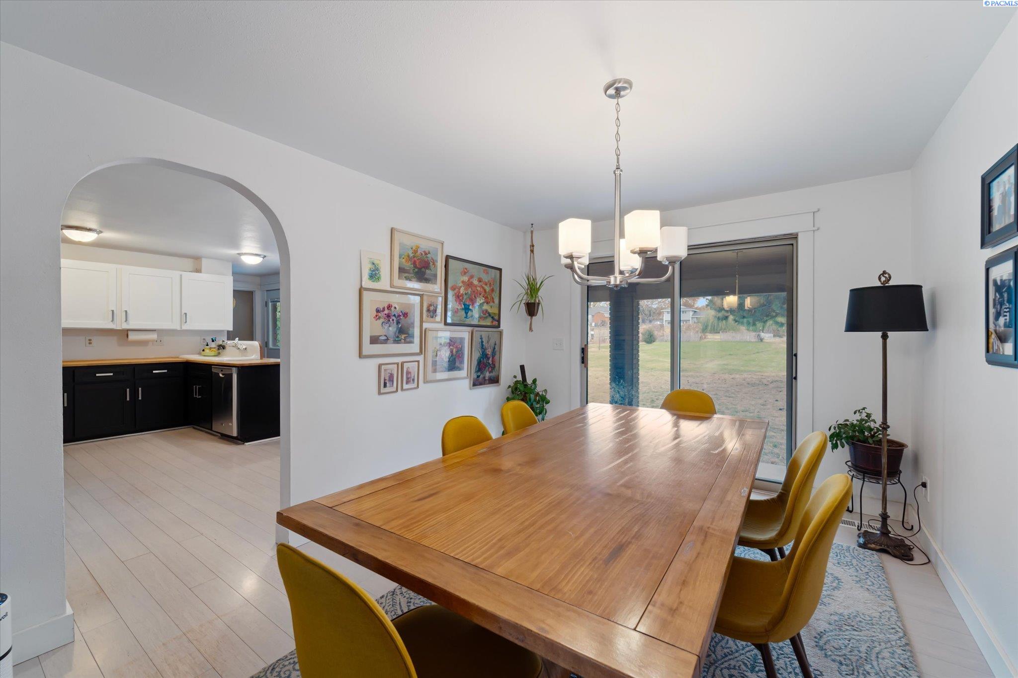 Dining room with a long wooden table, mustard-yellow chairs, and sliding glass doors to the yard.