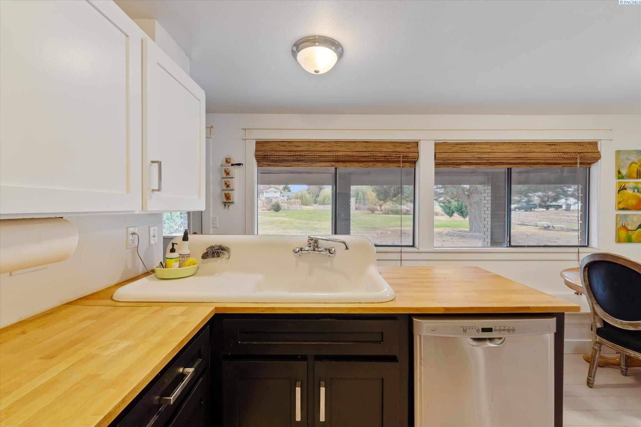 Kitchen with a large farmhouse sink, butcher-block counters, and wide windows overlooking the yard.
