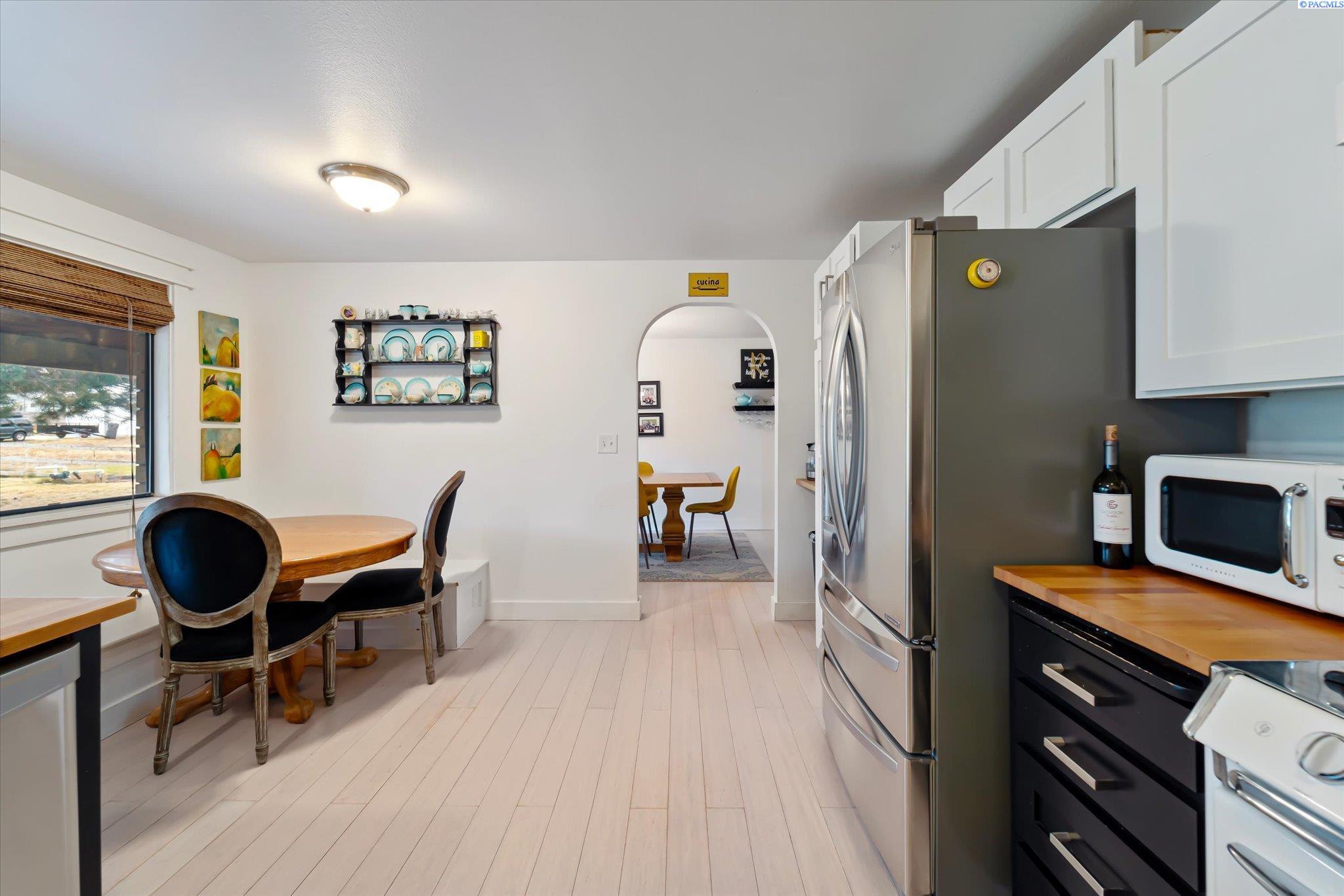 Kitchen with stainless steel appliances, white cabinets, and a dining table beside the window.