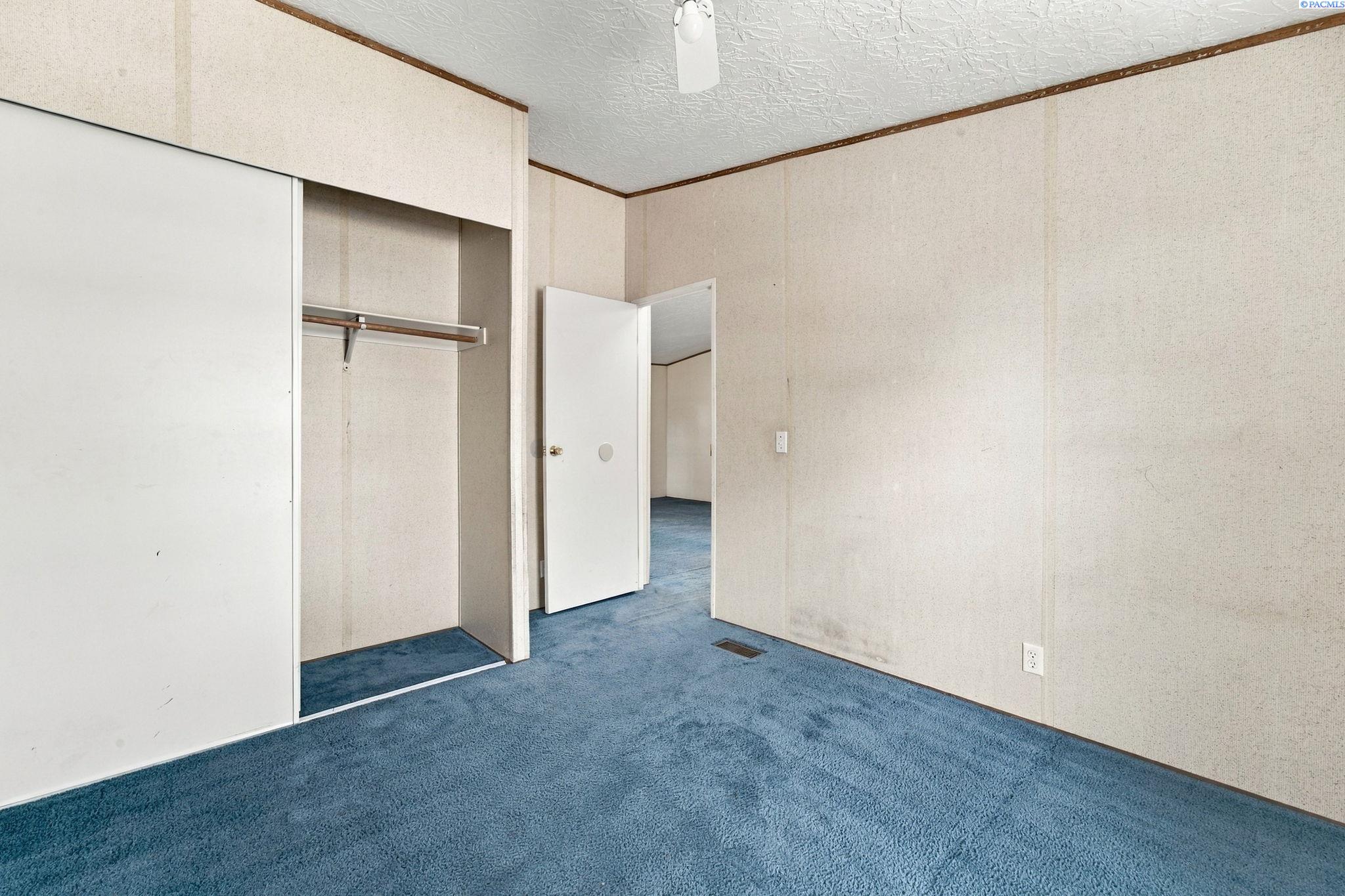 Empty carpeted room with a sliding-door closet and an open doorway.