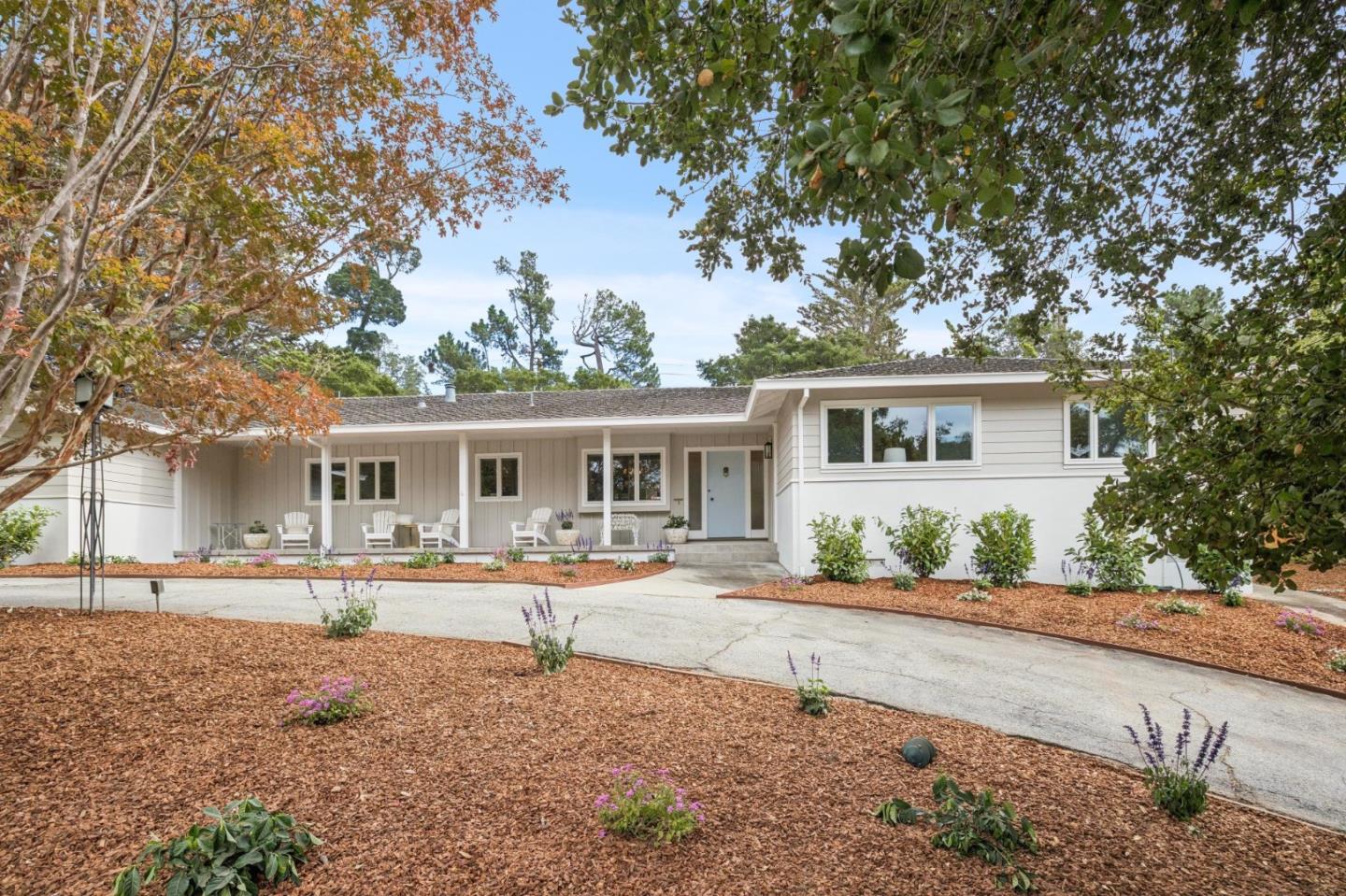 White ranch-style home with a covered porch, blue front door, and landscaped yard.