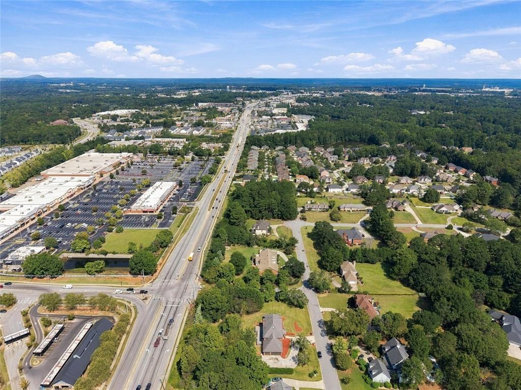 Aerial view of a Conyers neighborhood, shopping center, and highway amid wooded areas.