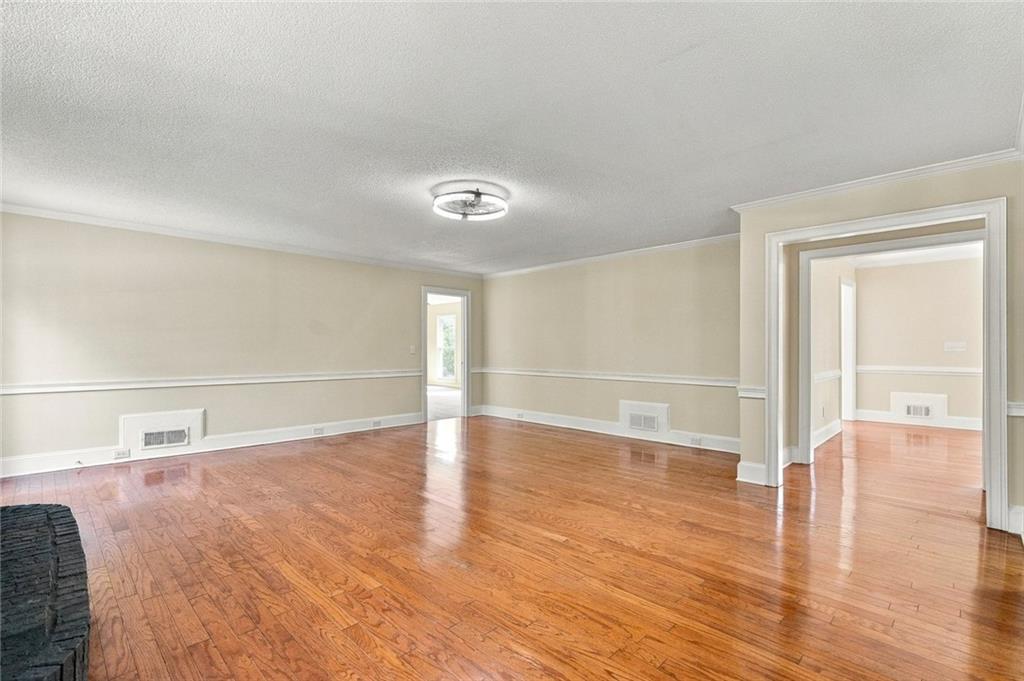 Vacant living room with polished hardwood floors and doorways to adjoining rooms.