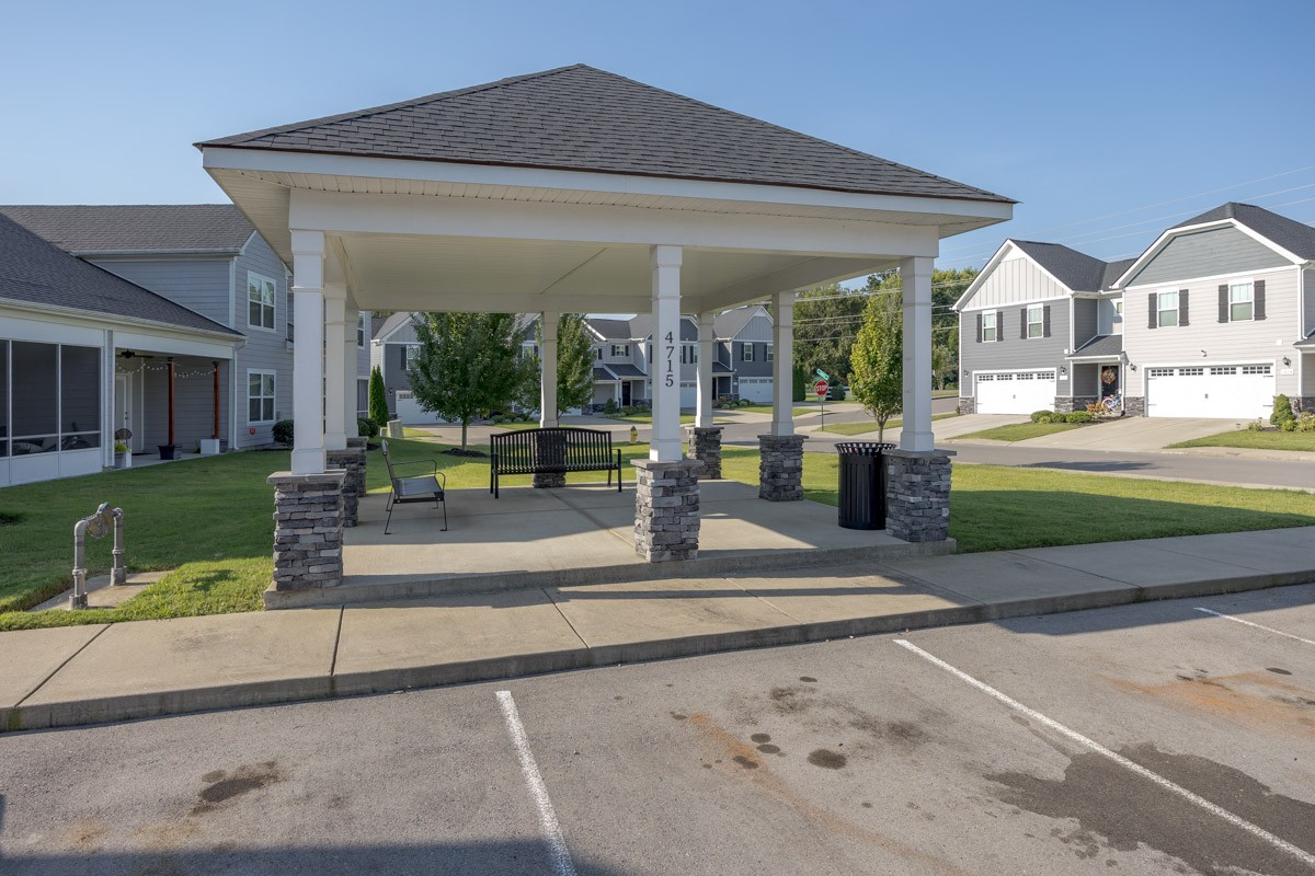 Covered community pavilion with stone-based columns and benches, surrounded by townhomes.
