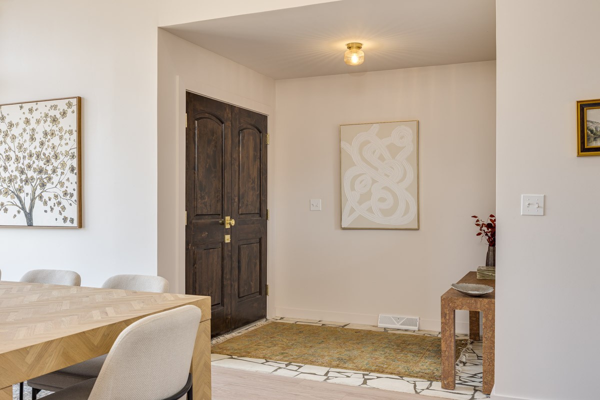 Home entryway with a dark wood double door and patterned tile flooring beside the dining area.
