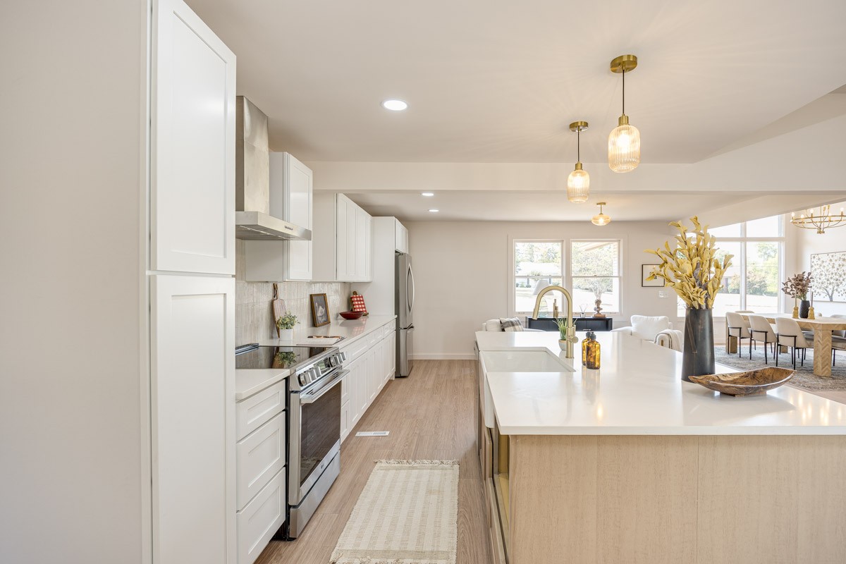 Bright kitchen with white cabinets, stainless appliances, and a large island opening to the dining area.