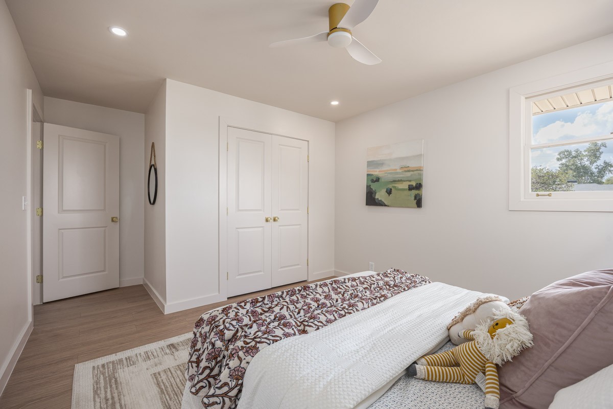 Bedroom with a white paneled closet, ceiling fan, and bed with patterned bedding.