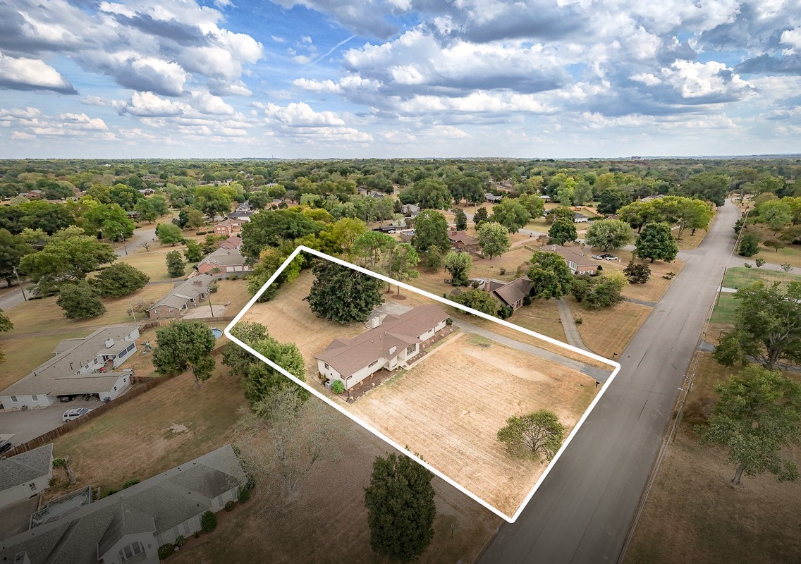 Aerial view of a single-story home and outlined lot beside a residential street.