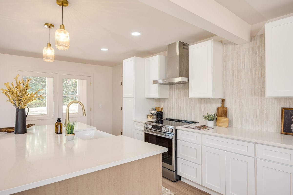 Kitchen with white cabinets, a stainless steel range, and a large island with a gold faucet.