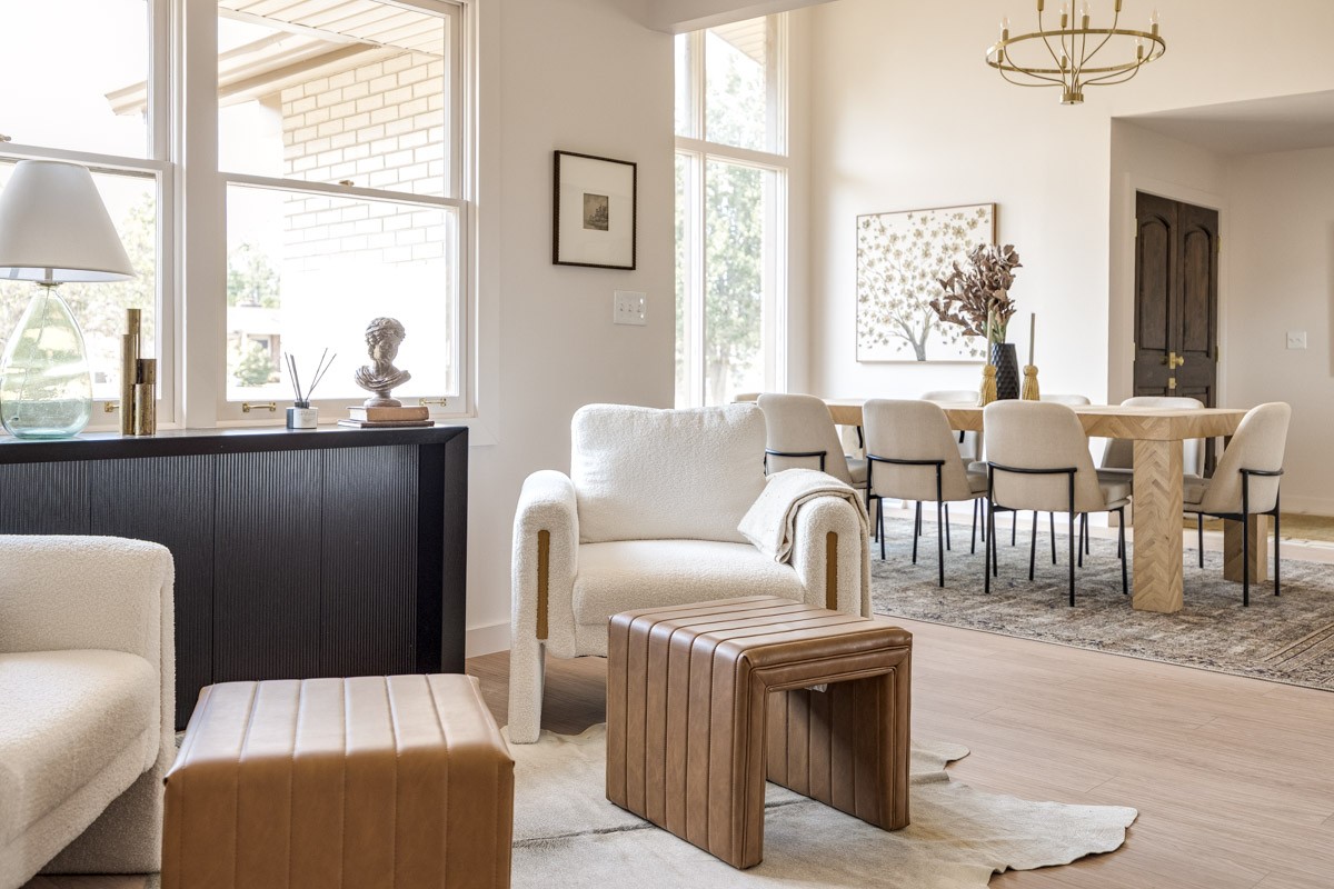 Open-plan living and dining room with tall windows, cream seating, and a long dining table.