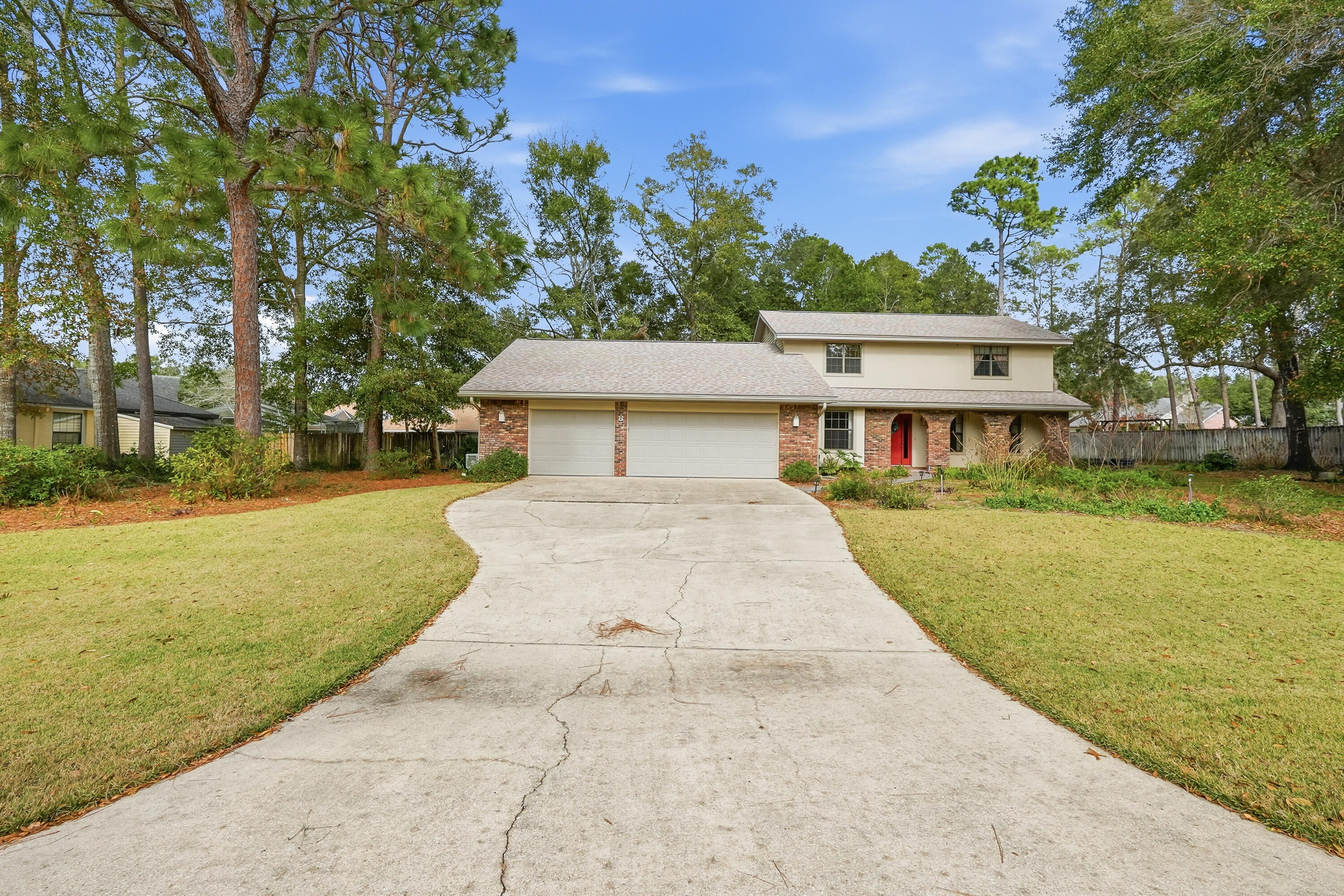 Two-story brick-and-siding home with a red front door and wide driveway to a two-car garage.