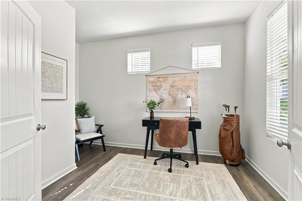 Furnished home office with a black desk, leather chair, world map, and golf bag.