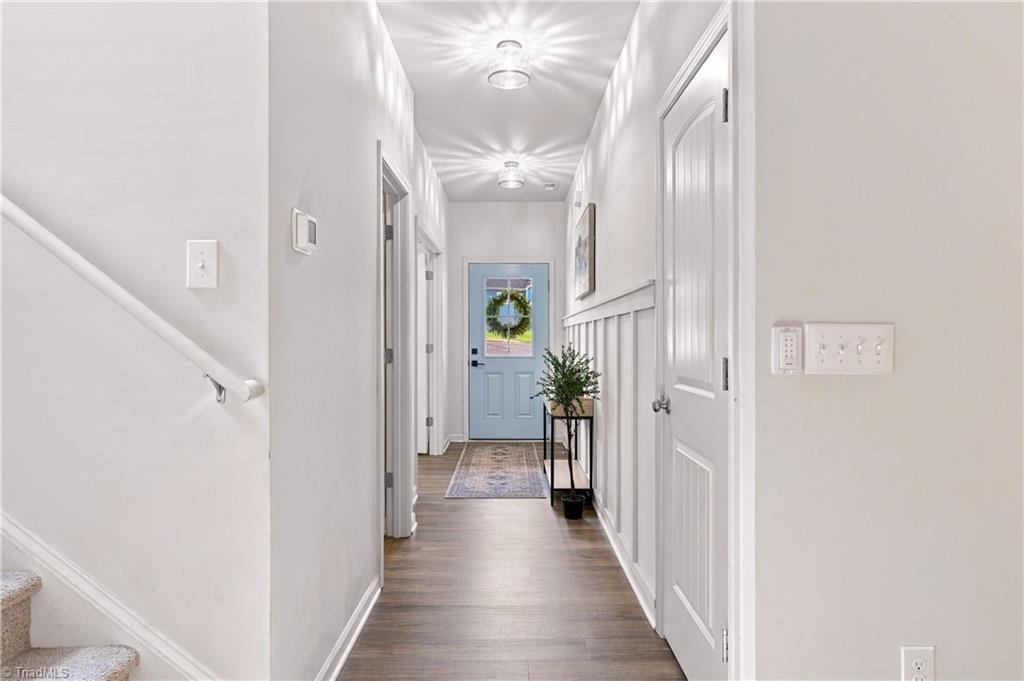 Hallway with gray wood-look floors, a patterned runner, and a blue front door.