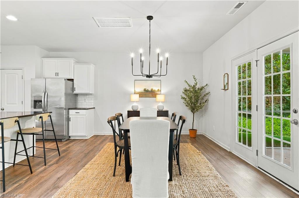 Dining area with a dark table, woven rug, white kitchen, and French doors to the yard.