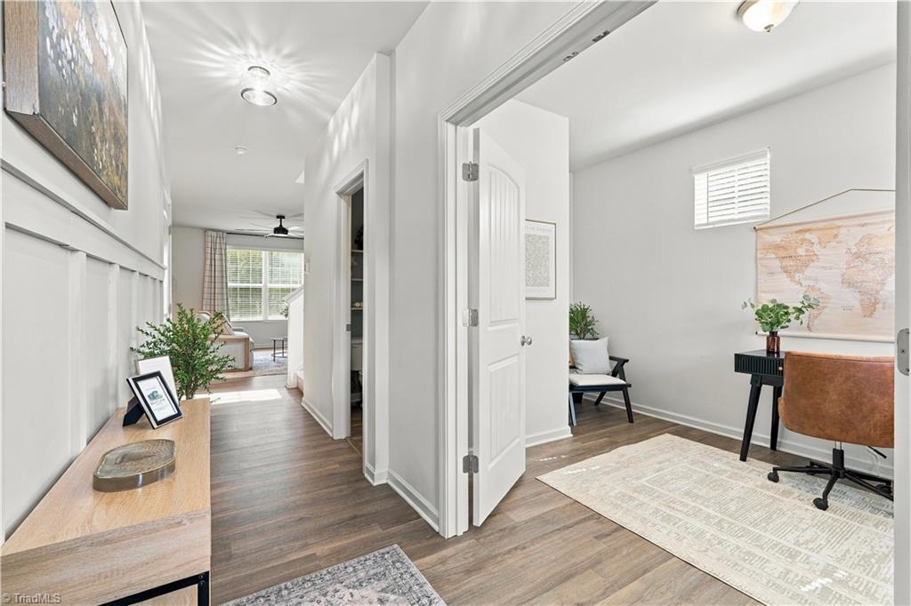 Home office with a doorway opening onto a bright hallway and adjoining living area.
