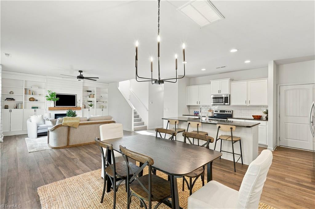 Open-plan kitchen and dining area with a large island, white cabinetry, and built-in living room shelves.