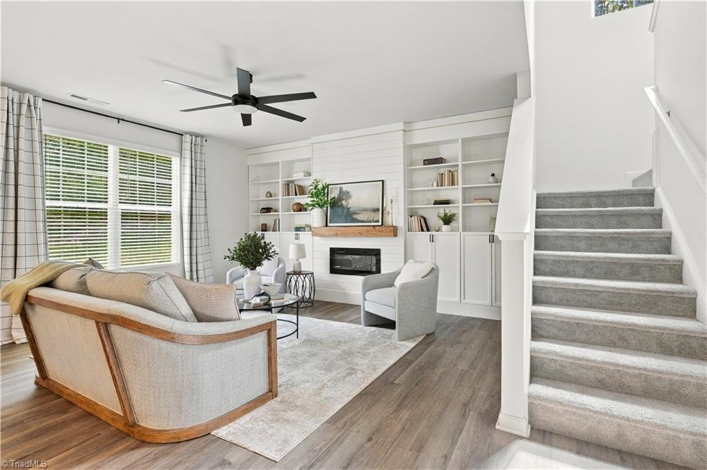 Furnished living room with built-in bookshelves, a fireplace, and stairs beside the seating area.