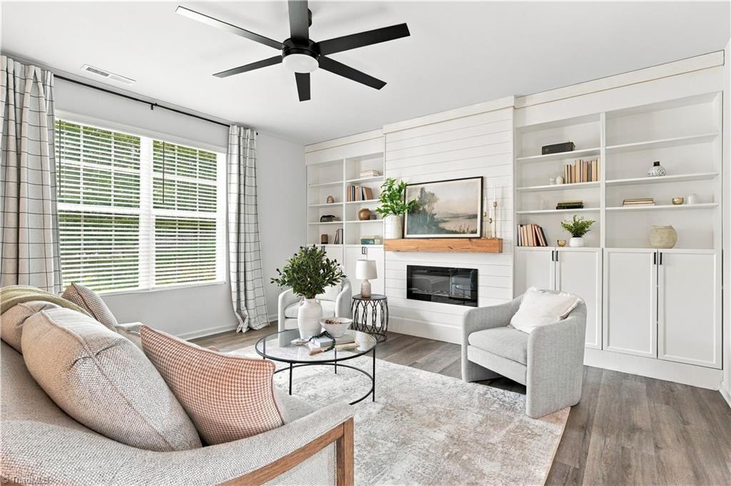 Living room with built-in white shelving, a gas fireplace, and a large window.