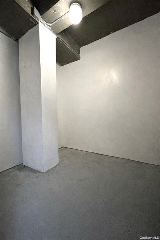 Empty utility room with a concrete floor, central support column, and exposed ceiling.