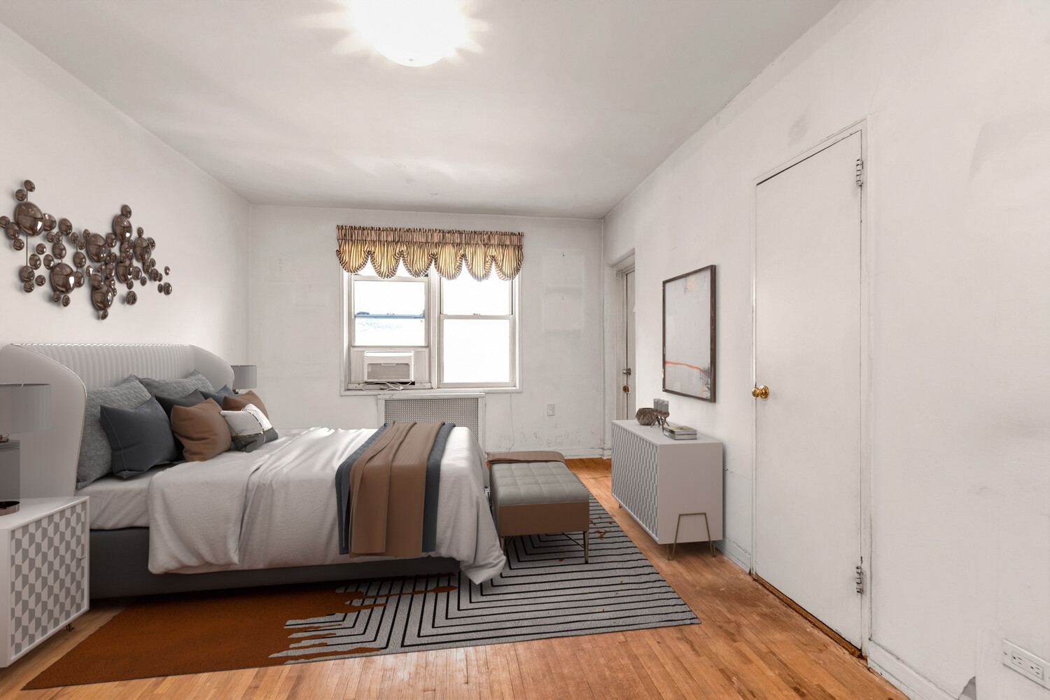 Bedroom with a large bed, patterned rug, hardwood floors, and a window air conditioner.