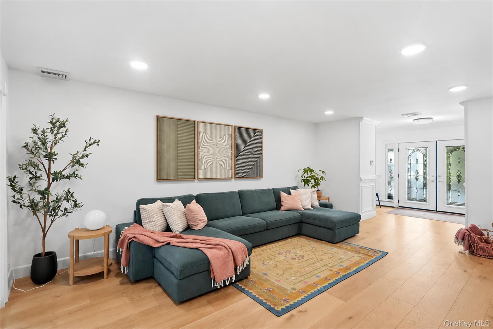 Living room with a teal sectional, patterned rug, and decorative glass entry doors.