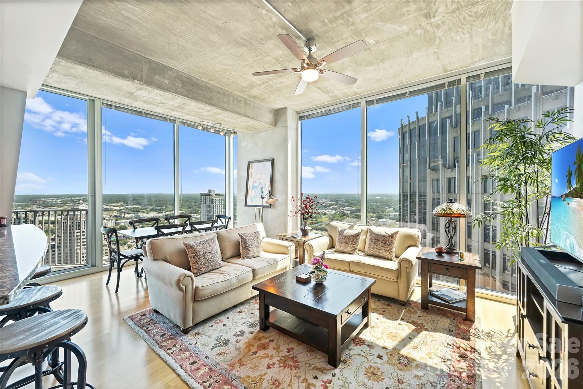 High-rise condo living room with cream sofas and floor-to-ceiling windows overlooking the city.