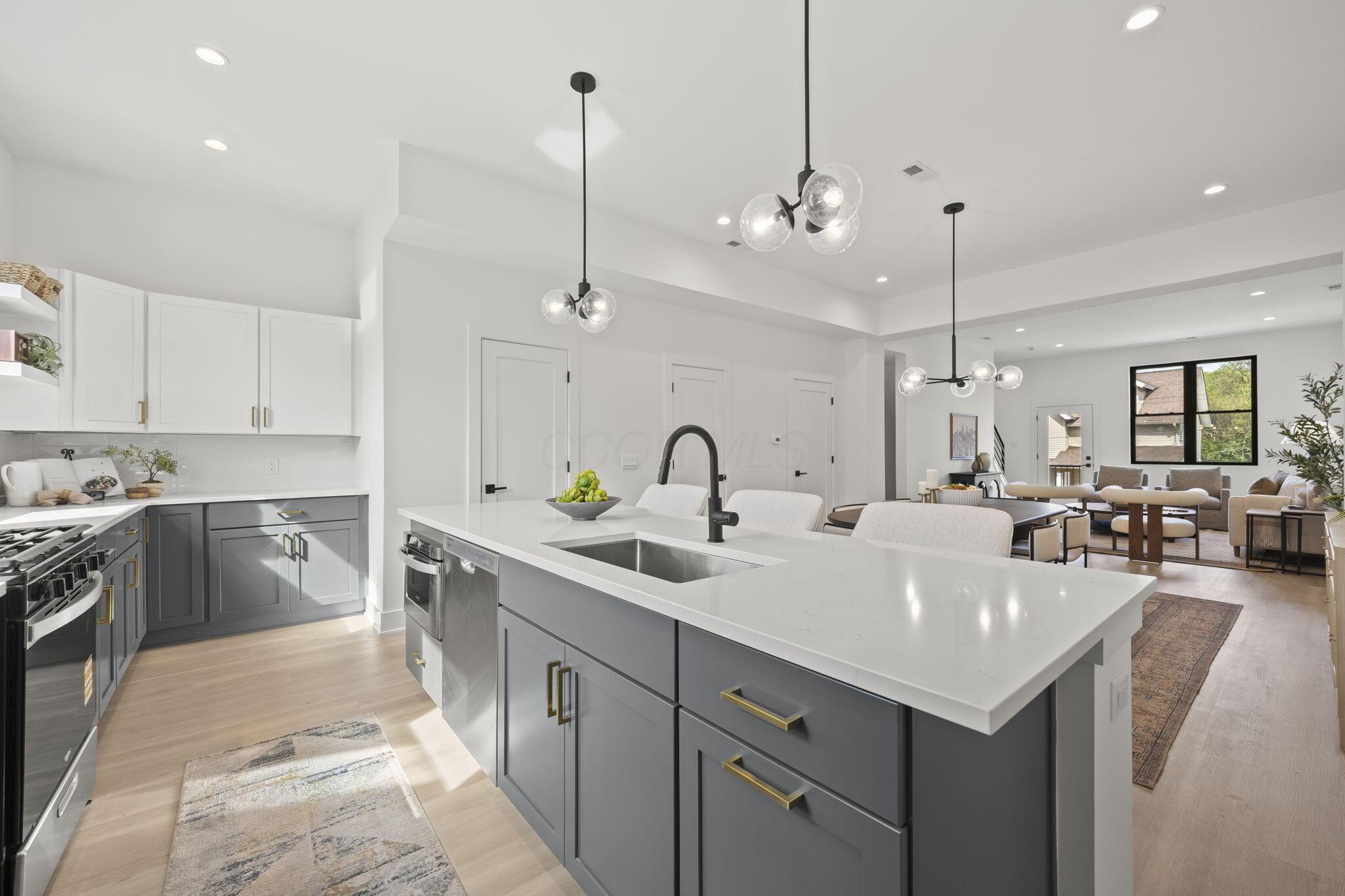 Open-plan kitchen with a large gray island and white counters, opening onto dining and living areas.