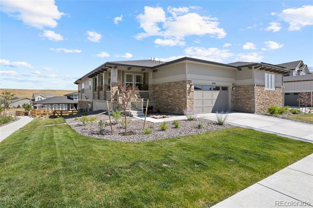 Modern single-story home with stone accents, a two-car garage, landscaped garden, and green lawn.