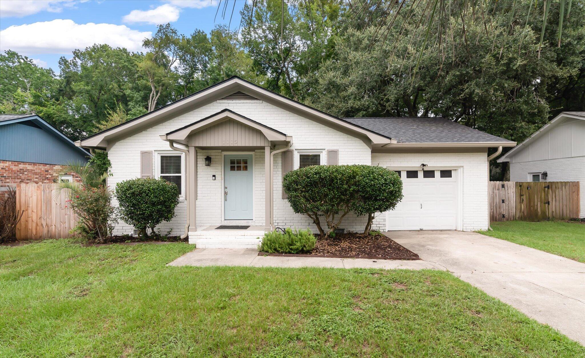 White brick house with a pale blue front door, attached garage, and neatly trimmed shrubs.