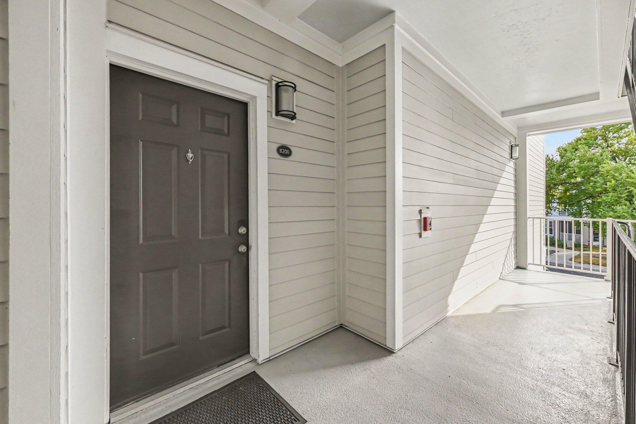 Home entrance with dark front door marked 8200 and a bright covered walkway.