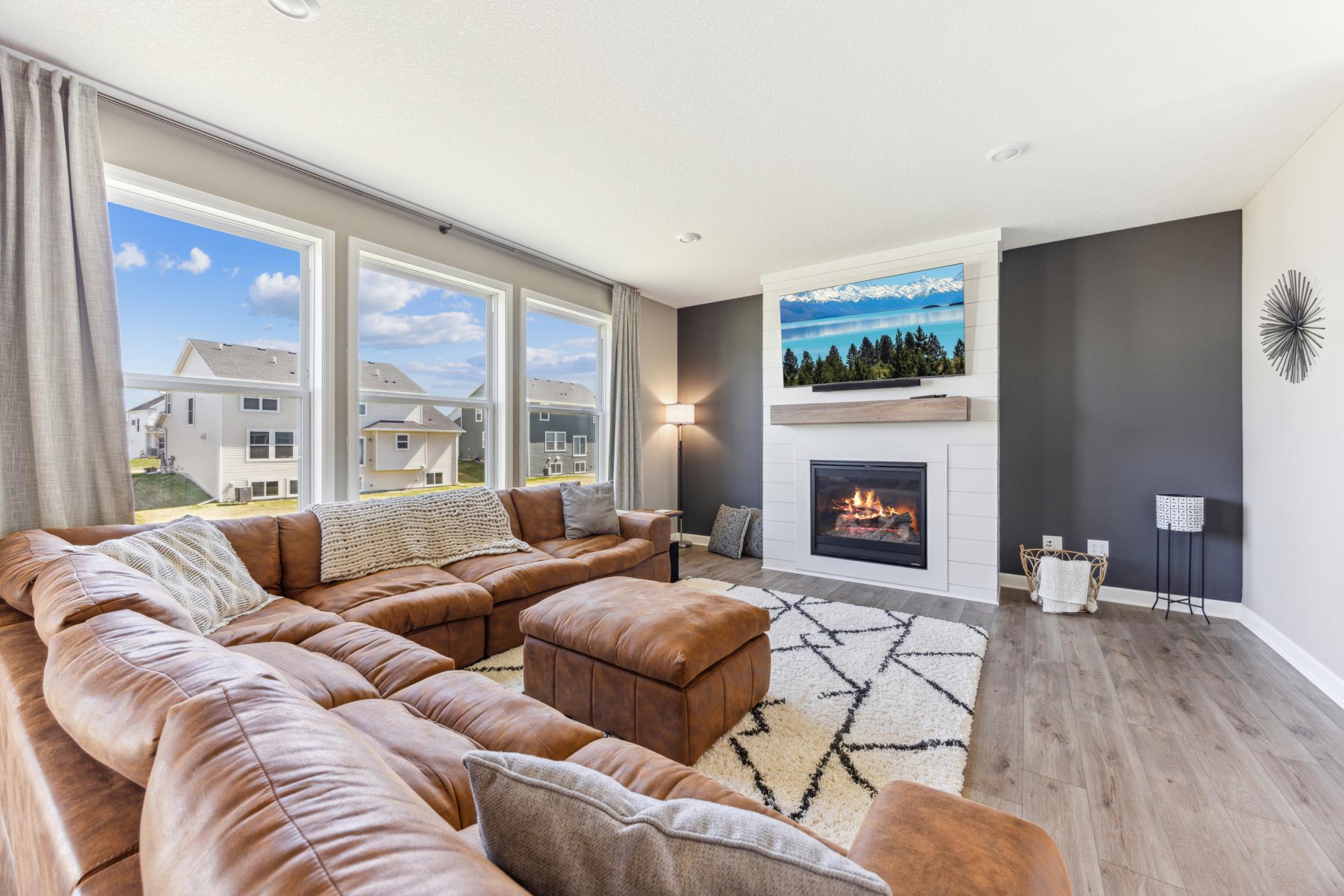 Living room with a brown sectional, geometric rug, and white fireplace with a dark accent wall.