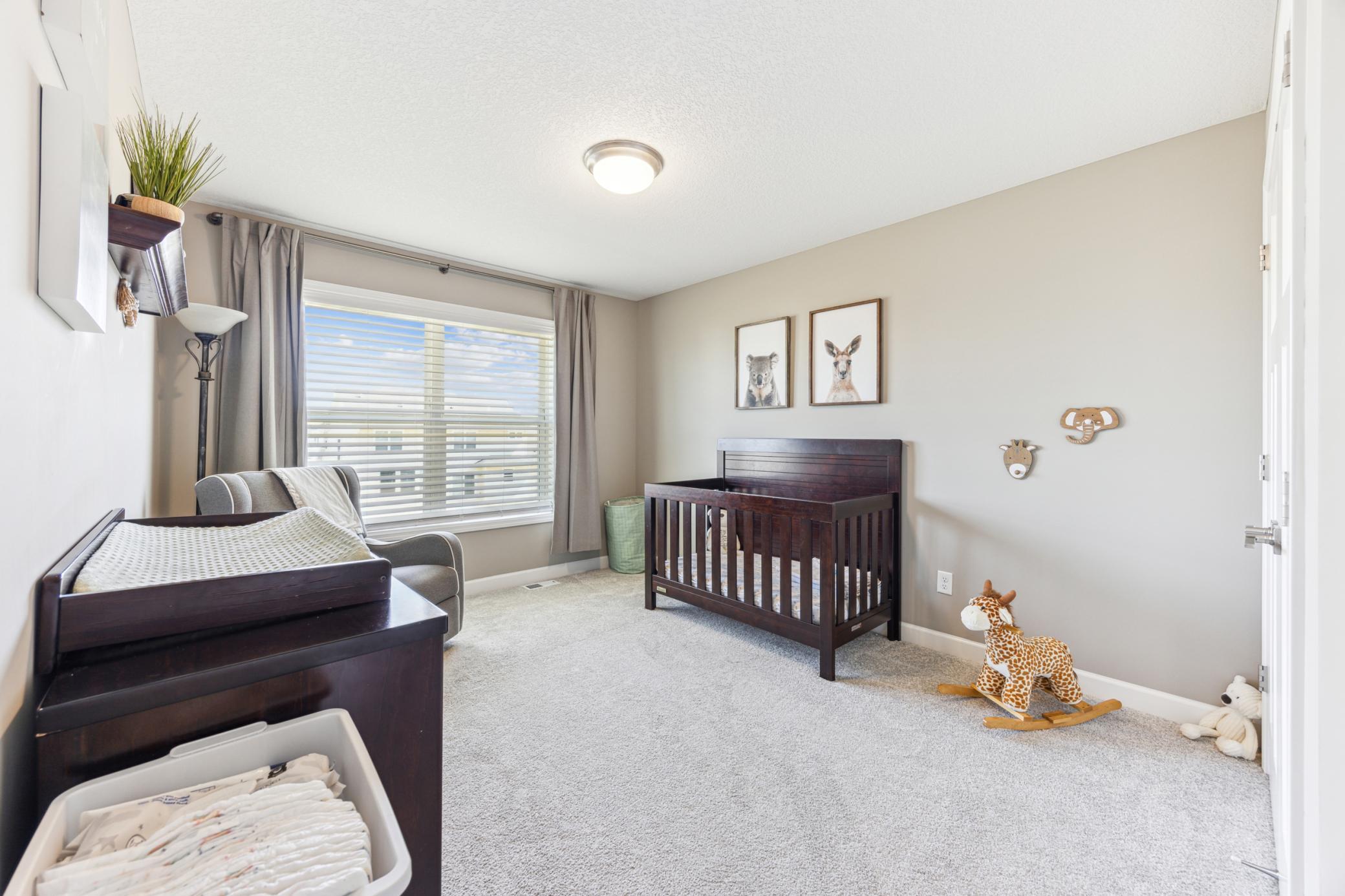 Furnished nursery with a dark wood crib, changing table, and gray rocking chair.