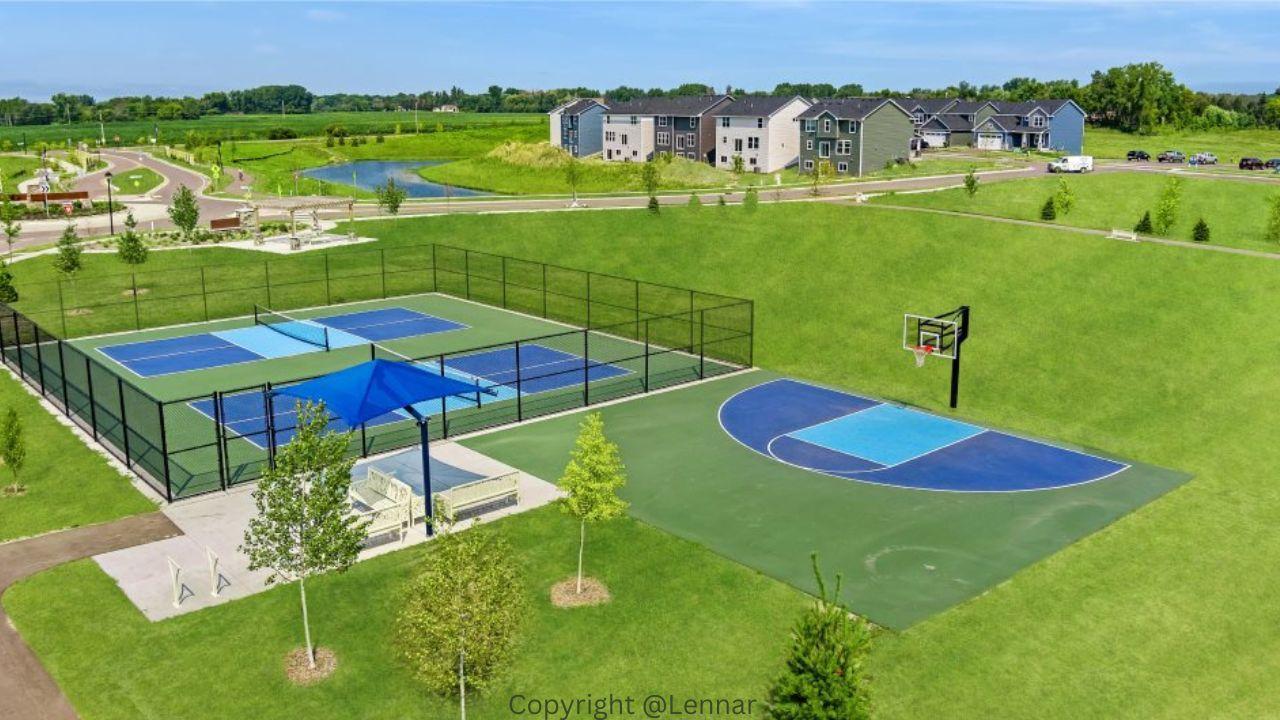 Neighborhood recreation area with fenced courts and a basketball court beside nearby homes.