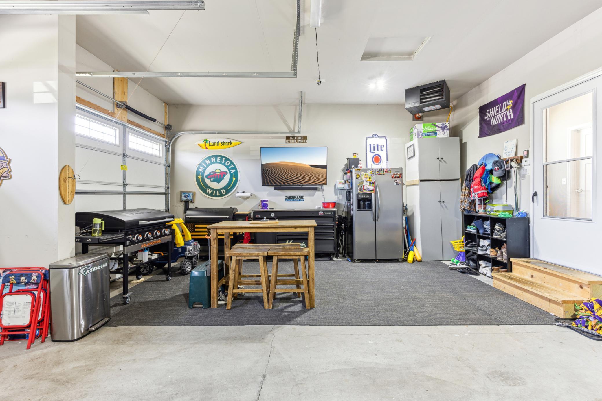 Finished garage with a grill, worktable, tool chests, refrigerator, and Minnesota Wild decor.