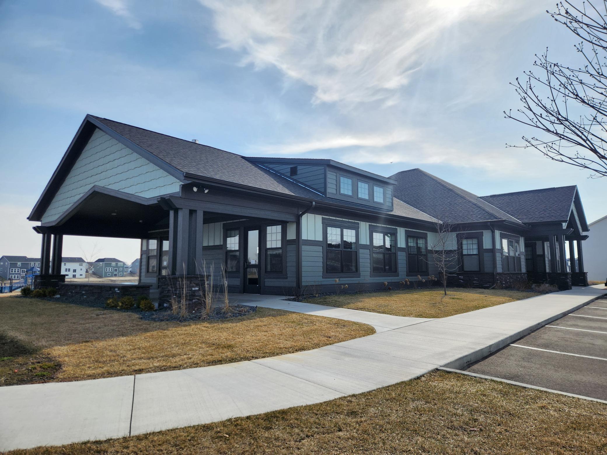 Dark-sided home with multiple gabled roofs, a covered porch, and a walkway along the front.