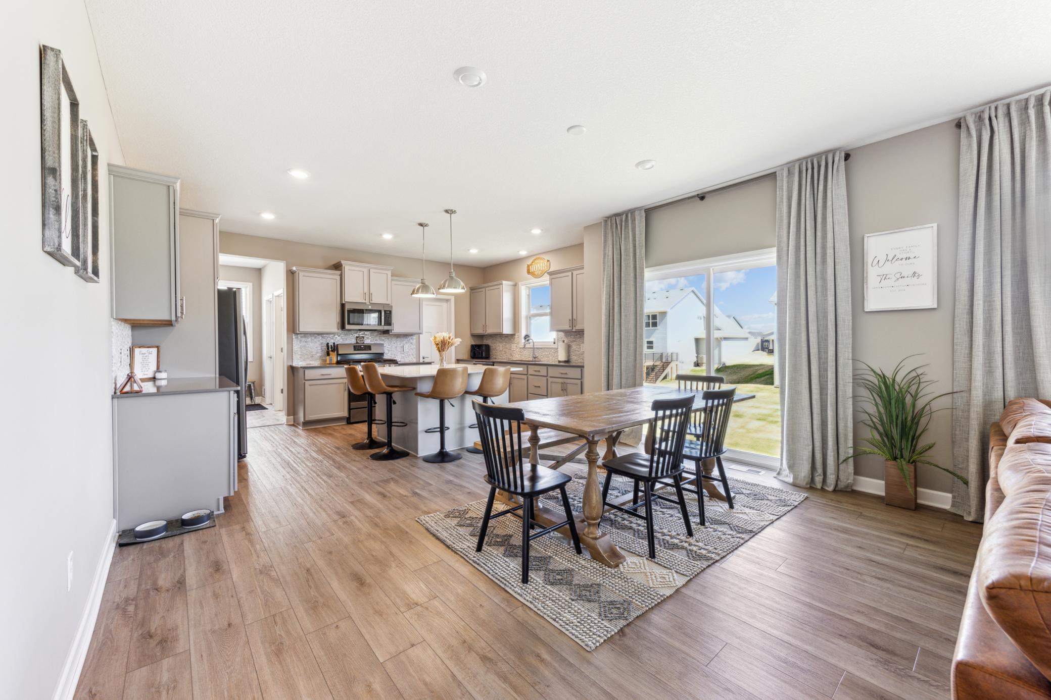Open-plan kitchen and dining area with a central island, wood table, and large sliding glass doors.