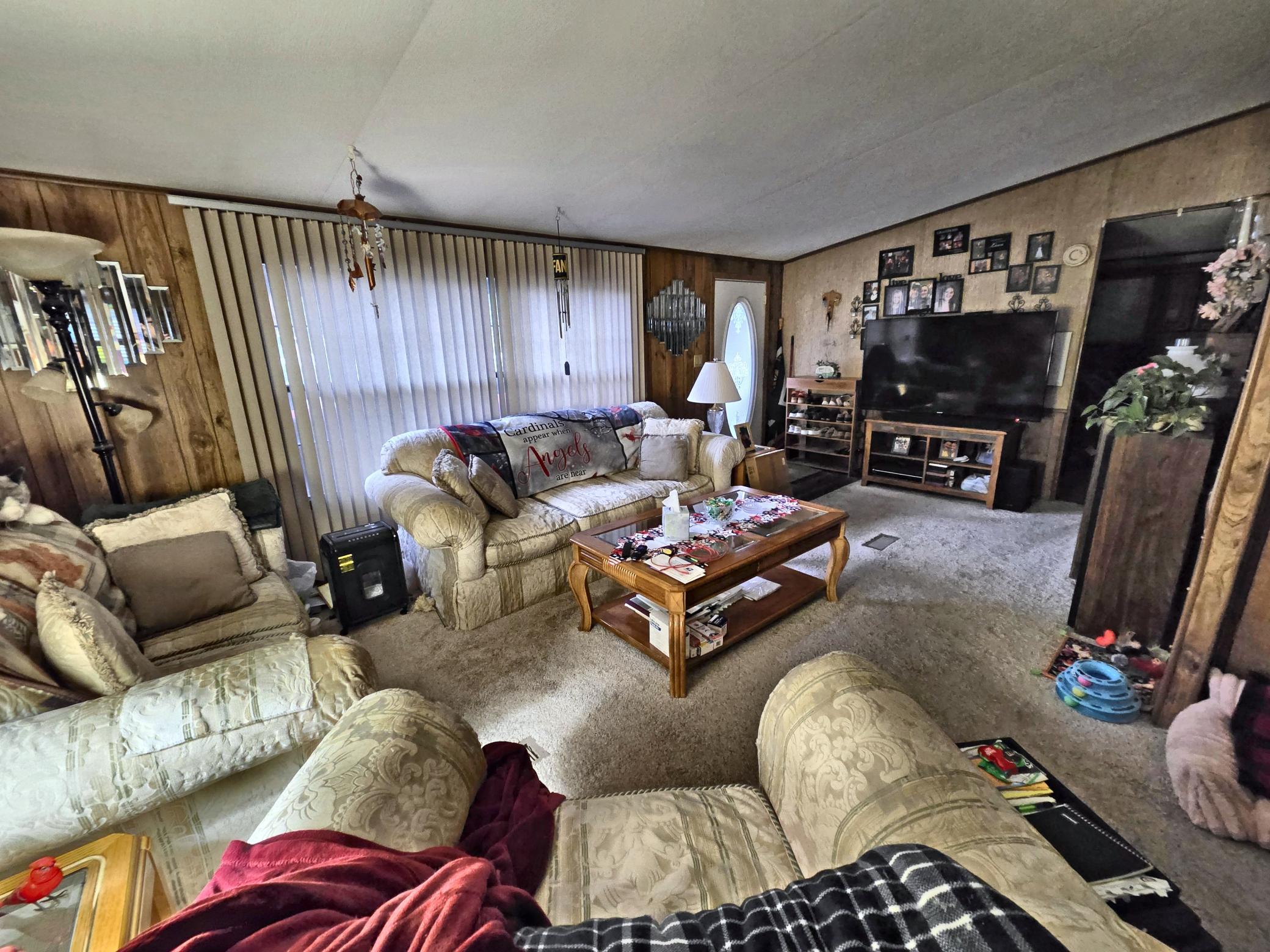 Living room with patterned sofas, wood-paneled walls, and a television area.