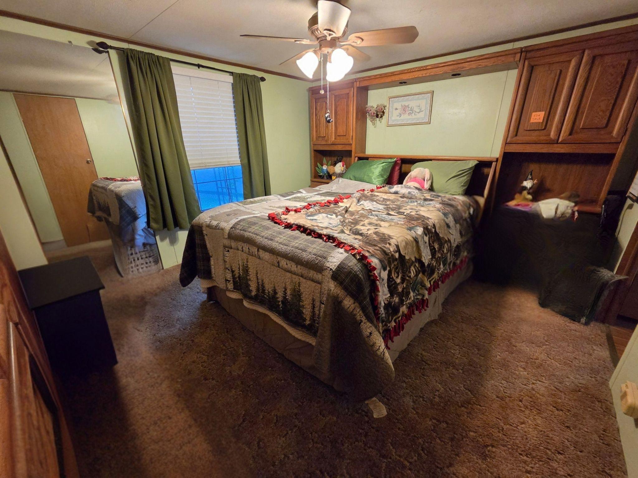 Bedroom with a patterned quilted bed, built-in wood cabinetry, mirrored doors, and a ceiling fan.