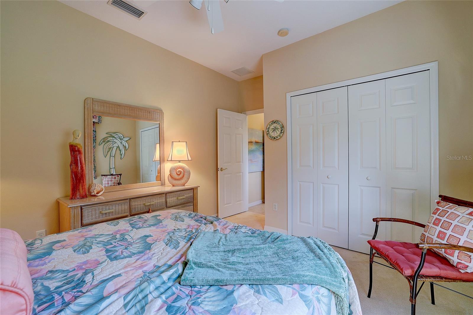 Furnished bedroom with a floral bed, turquoise throw, and white double closet doors.