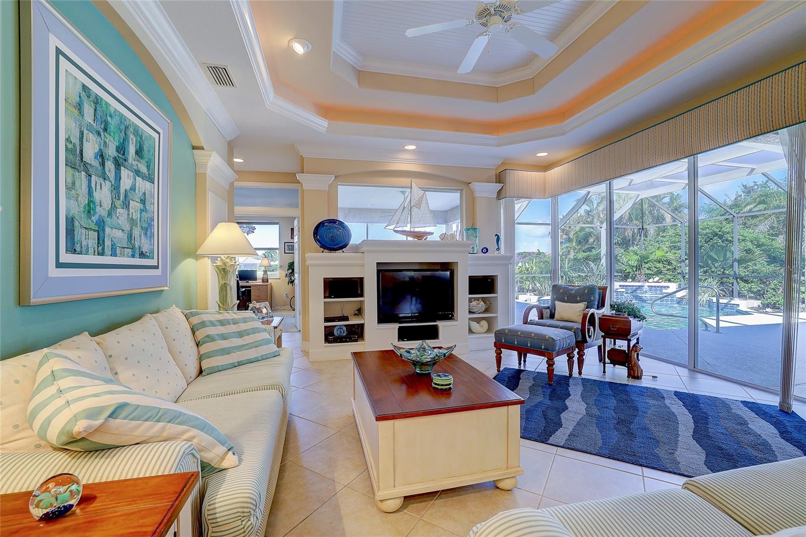 Living room with a built-in entertainment center and sliding doors overlooking a screened pool patio.