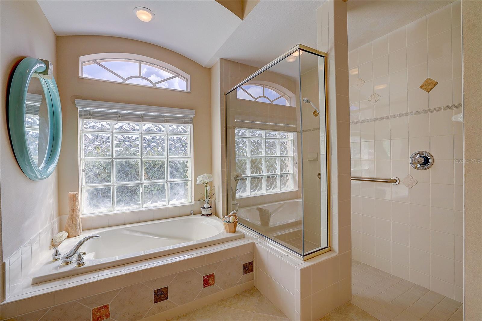 Bathroom with a built-in soaking tub, glass-enclosed shower, and tall glass-block windows.