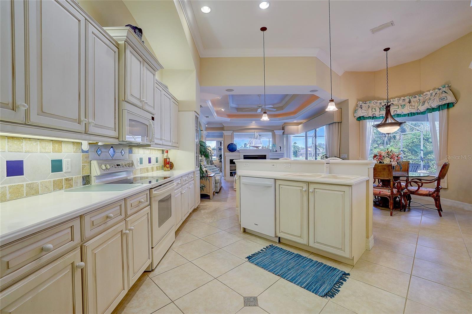 Kitchen with cream cabinetry and central island, opening to a dining area and living room.