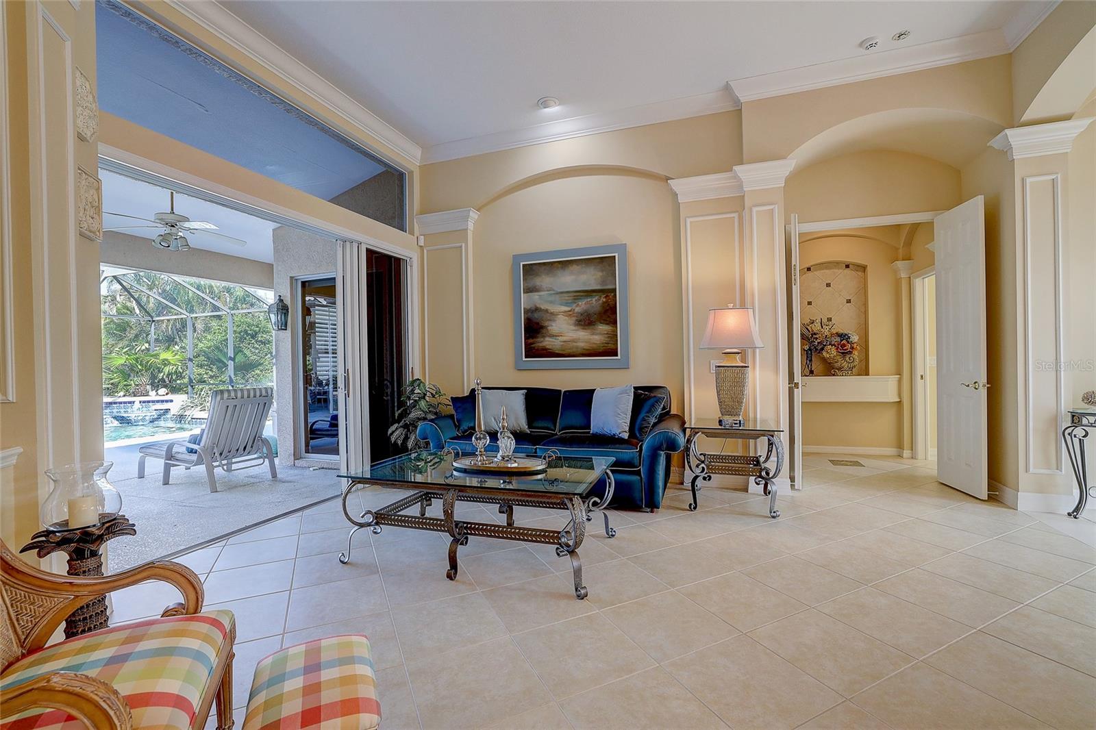 Living room with a blue sofa and glass coffee table beside sliding doors to a screened pool lanai.