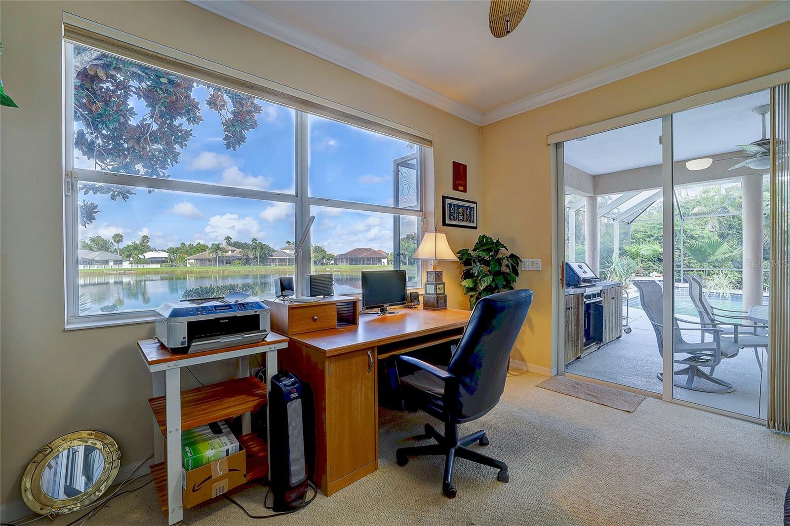 Home office with a lake view and sliding doors to a screened pool lanai.