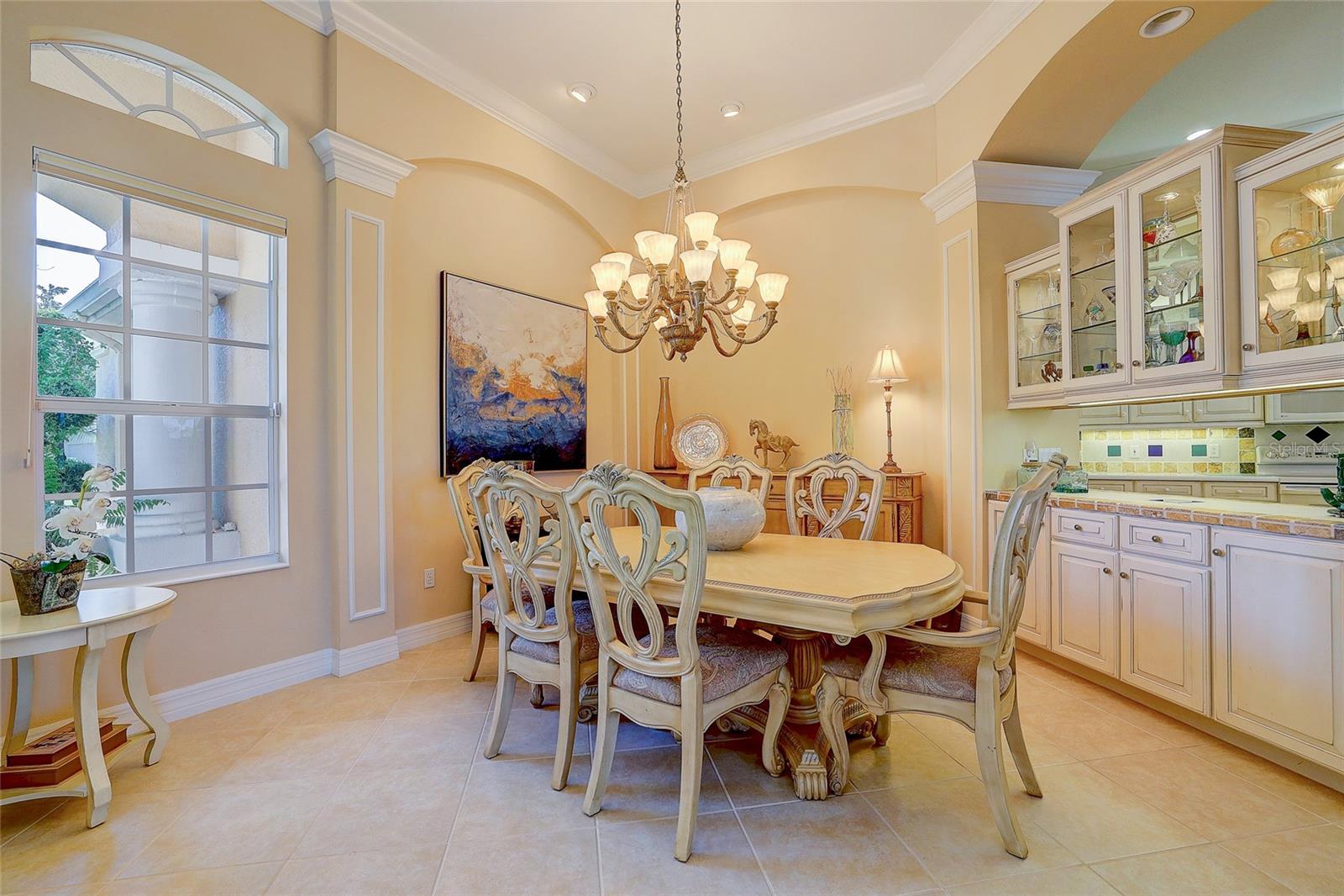 Dining room with an ornate oval table, carved chairs, chandelier, and glass-front built-in cabinets.